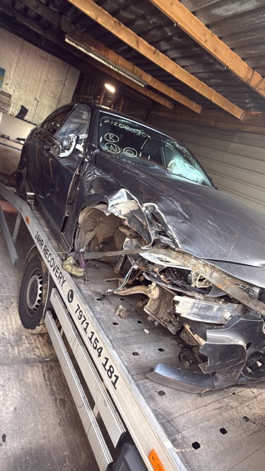 BMW with severe front-end accident damage delivered on a recovery truck